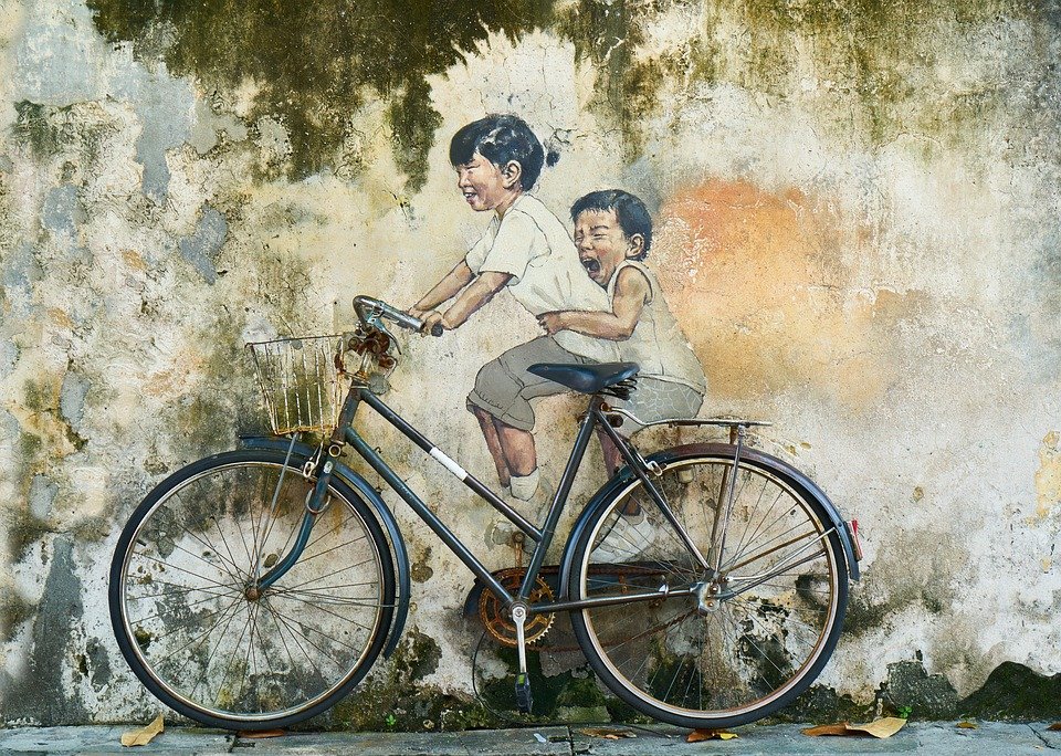 Graffiti på væg afbilleder to børn på en cykel